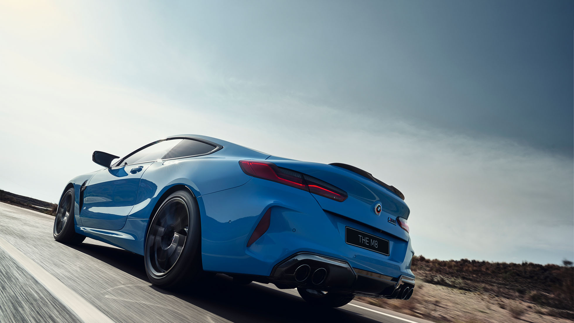 BMW M8 Competition Coupé, three-quarter side view. BMW M8 Competition Coupé in Marina Bay Blue metallic, driving three-quarter side view in front of starry sky.